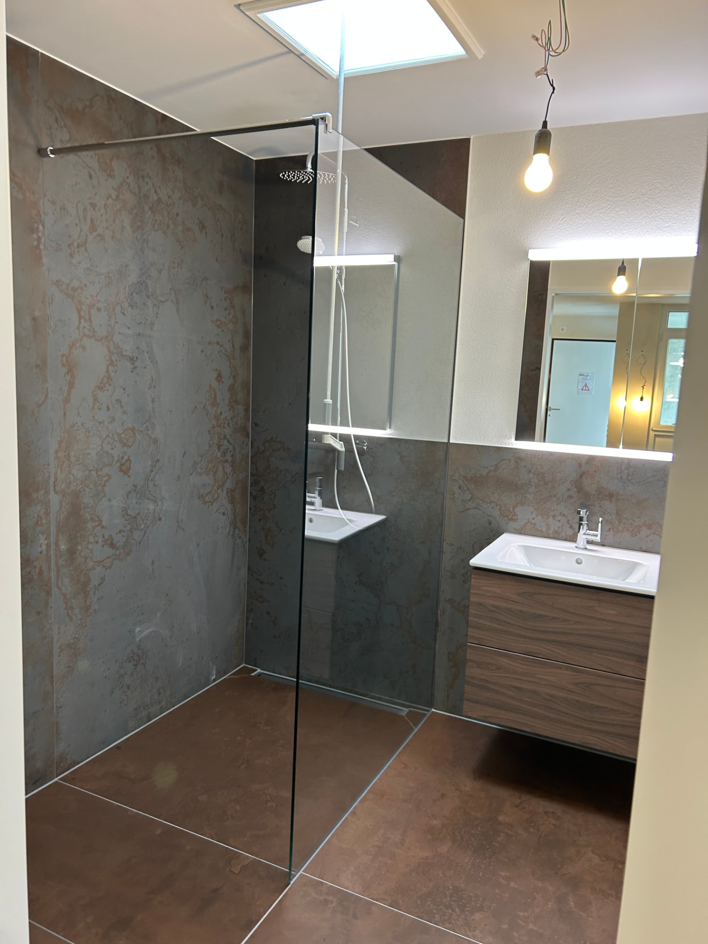 Neue offene Dusche mit Steinfliesen und Waschtisch der Wohnung in Therwil nach dem Umbau