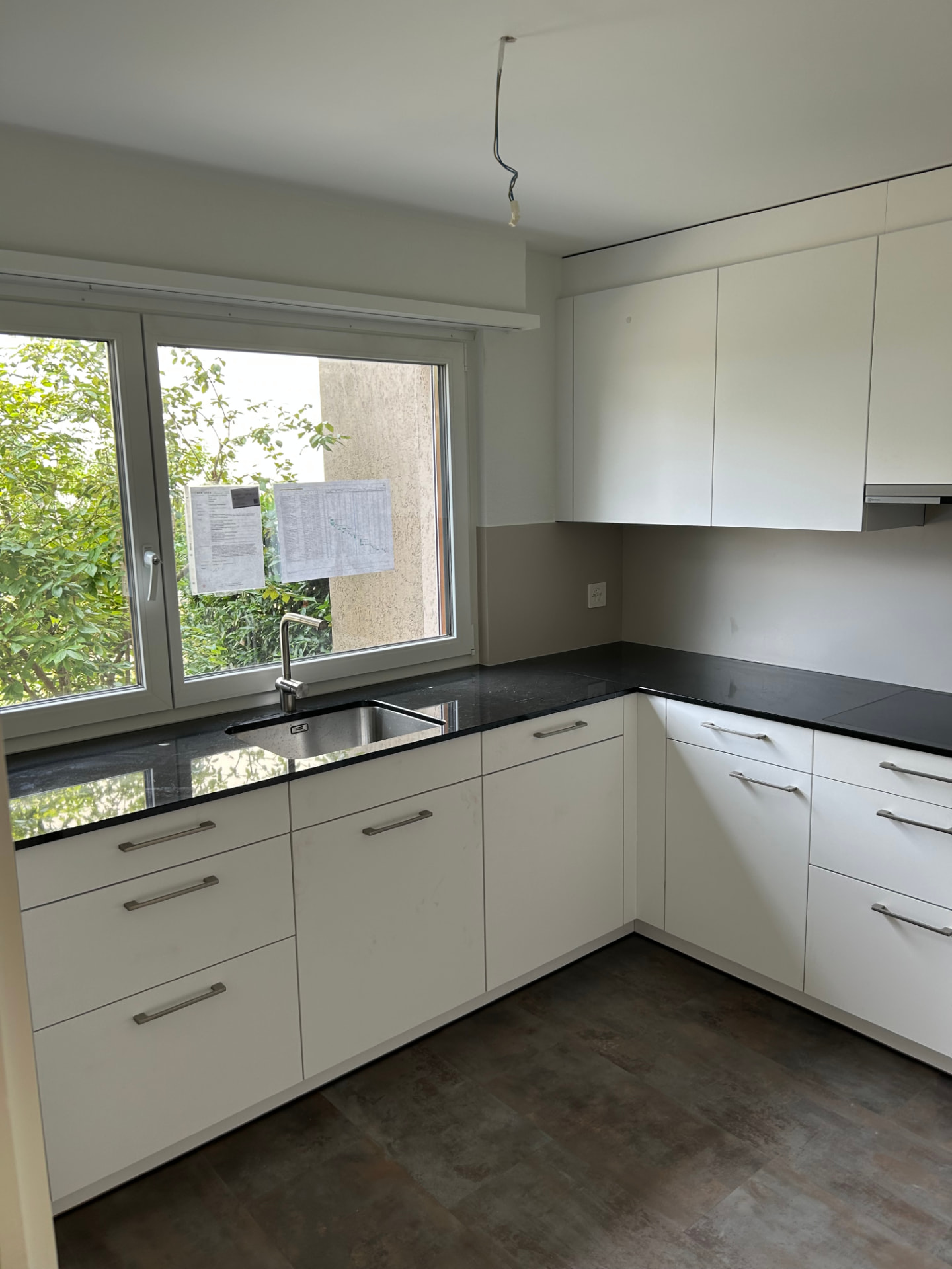 Neue weisse Küche mit schwarzem Naturstein der Wohnung in Muttenz nach dem Umbau